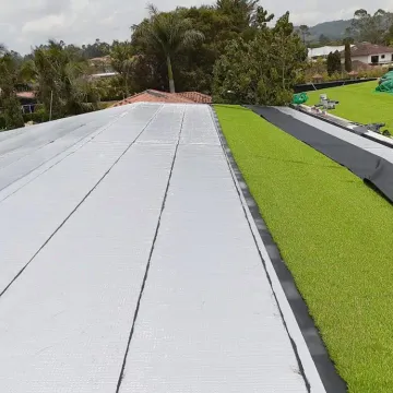 Cubierta larga impermeabilizada con manto aluminio y zona verde, obra de Madepinos