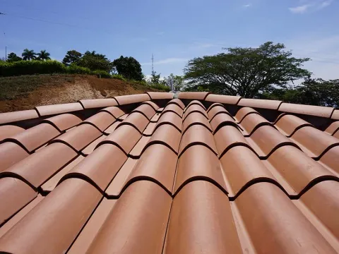 Hileras de teja de barro sobre una cubierta bajo cielo azul, obra cerca de Medellín