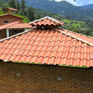 Casa campestre con teja de barro y montañas al fondo, obra cerca de Medellín