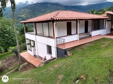 Casa de dos pisos con techo en teja de barro y paisaje de montaña, Antioquia
